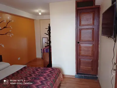 a bedroom with a bed and a wooden door at Nature Home Cusco in Cusco