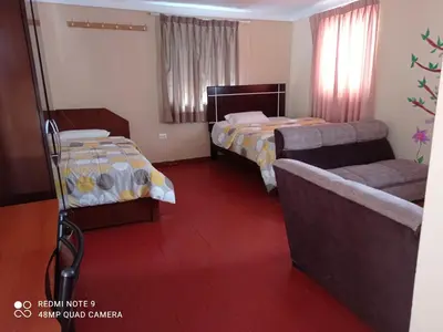 a hotel room with two beds and a couch at Nature Home Cusco in Cusco