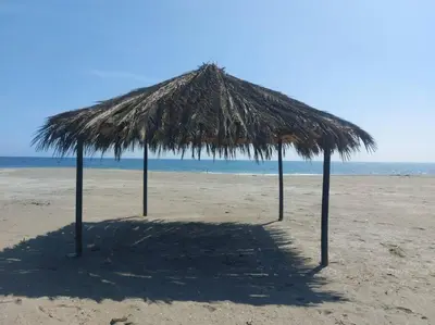 a straw umbrella on a beach with the ocean at Playa ChinchaHouse - Agradable casa de playa en Chinchaycamac in Chincha Baja