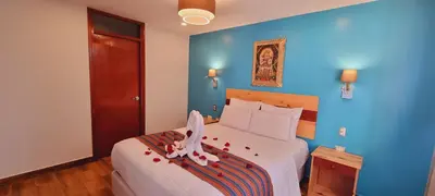 a bedroom with a large white bed with blue walls at HOTEL LUZ GARDEN in Machu Picchu