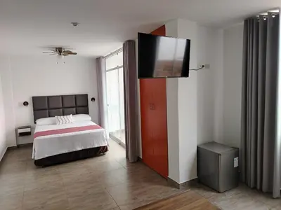 a bedroom with a bed and a flat screen tv at Casa Yuraq Hotel Boutique in Chincha Alta