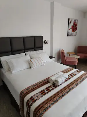 a bedroom with a large white bed with towels on it at Casa Yuraq Hotel Boutique in Chincha Alta