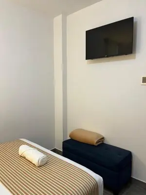 a room with a bed and a blue ottoman and a television at Casa Yuraq Hotel Boutique in Chincha Alta