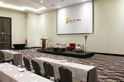 a conference room with tables and chairs and a screen at Sol de Oro Hotel & Suites in Lima