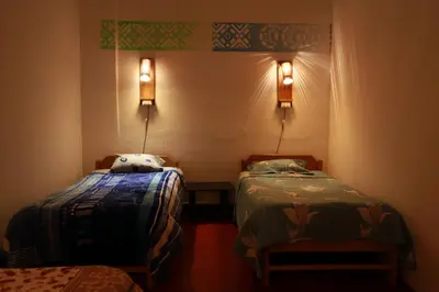 a room with two beds and two lights on the wall at Tiyana House in Cusco