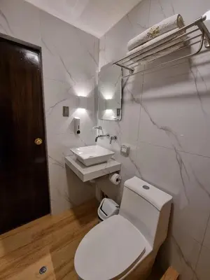 a white bathroom with a toilet and a sink at Hotel Rey in Huancayo