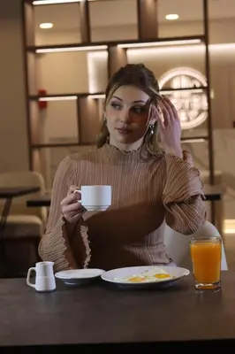 a woman sitting at a table with a cup of coffee at Hotel Rey in Huancayo