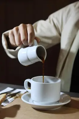 a person pouring coffee into a cup on a table at Hotel Rey in Huancayo