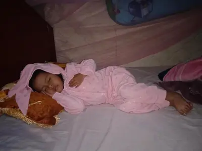 a baby laying on a bed with a teddy bear at Lia B&B Lucmabamba in Sahuayacu