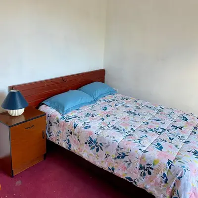 a bedroom with a bed and a night stand with a lamp at Departamento céntrico con terraza ideal para grupos in Ayacucho