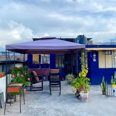 a blue house with a purple umbrella on a patio at Departamento céntrico con terraza ideal para grupos in Ayacucho