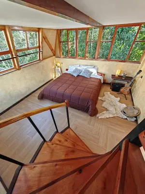 a bedroom with a bed in a room with windows at Casa al lado del Bosque in Oxapampa