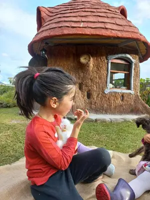 a young girl eating food in front of a bird house at Biosfera Lodge tipi para 3 personas in Oxapampa