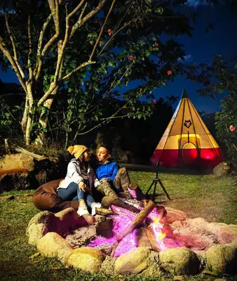 a group of people sitting around a fire with a tent at BIOSFERA LODGE GLAMPING tipi 2 personas in Oxapampa