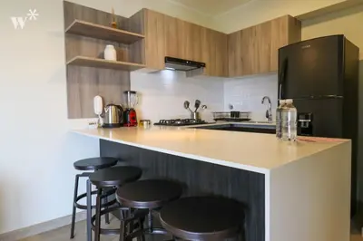 a kitchen with wooden cabinets and bar stools at El Sol by Wynwood House in Lima