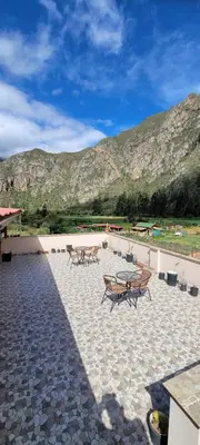 a patio with benches and tables with mountains in the background at Ayllu B&B Ollantaytambo in Ollantaytambo