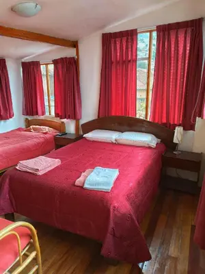 a bedroom with two beds and red curtains at Korilazos in Cusco