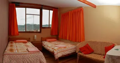 a bedroom with two beds and a window with red curtains at Korilazos in Cusco