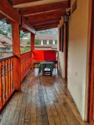 a balcony with a red couch and a table at Korilazos in Cusco