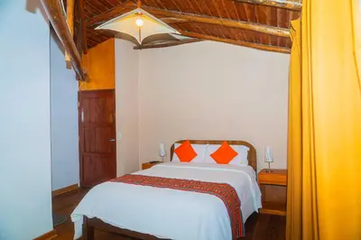 a bedroom with a white bed with orange pillows at Casa de Ollanta ByB in Ollantaytambo