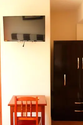 a table and a chair with a television on a wall at Hotel Conquistador in Andahuaylas