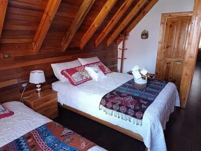 two beds in a room with wooden walls at La Cabaña de Mari in Oxapampa