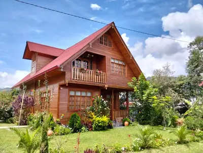 a wooden house with a porch and a balcony at La Cabaña de Mari in Oxapampa