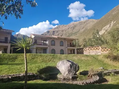 a house on a hill with a palm tree and a rock at Inti Punku Valle Sagrado Hotel in Urubamba