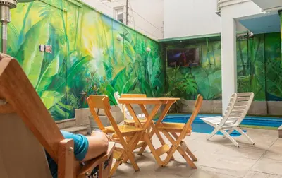 a room with a table and chairs and a pool at Rainbow Hostel in Lima