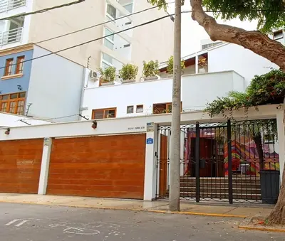 a building with a fence and a garage at Rainbow Hostel in Lima