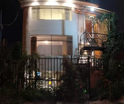 a white house with a staircase in front of it at night at Runa Apartamentos in Cusco