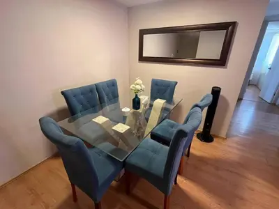 a dining room with a glass table and blue chairs at Hermoso departamento totalmente amoblado - Lte San Miguel in Lima