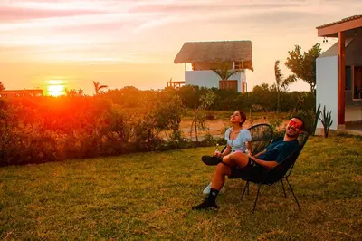 a man and a woman sitting in a chair at sunset at HOP PRAIA exclusiva laguna y playa en Chincha in Chincha Baja