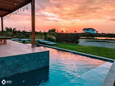 a swimming pool with a sunset in the background at HOP PRAIA exclusiva laguna y playa en Chincha in Chincha Baja