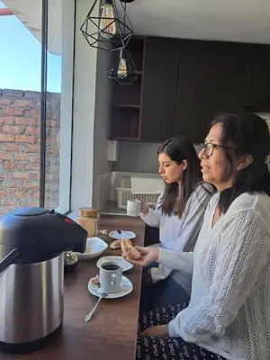 two women sitting at a table in a kitchen at Casa Kutimuy in Ayacucho