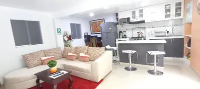 a living room with a white couch and a kitchen at Cusco Centro Home in Cusco