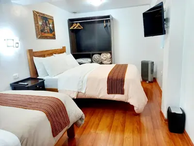a hotel room with two beds and a flat screen tv at Cusco Centro Home in Cusco