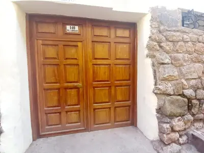 a wooden door with a sign on it next to a stone wall at Cusco Centro Home in Cusco