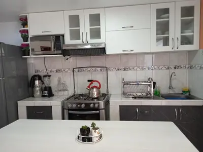 a kitchen with white cabinets and a tea kettle on a stove at Cusco Centro Home in Cusco