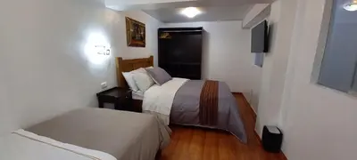 a small room with two beds and a television at Cusco Centro Home in Cusco