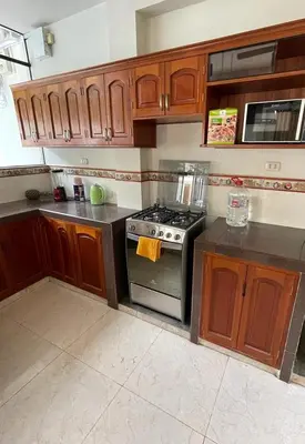 a kitchen with wooden cabinets and a stove at Casa completa piscina 3 Habitaciones en Chanchamayo in La Merced
