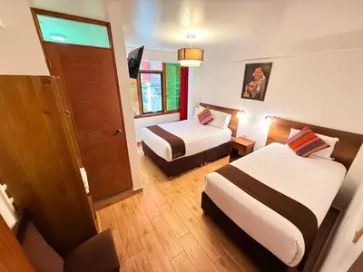 a hotel room with two beds and a window at Inti Pacha Palace Machupicchu in Machu Picchu