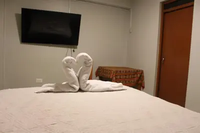 two towel swans sitting on top of a bed at LA CASA DEL VISITANTE in Cusco