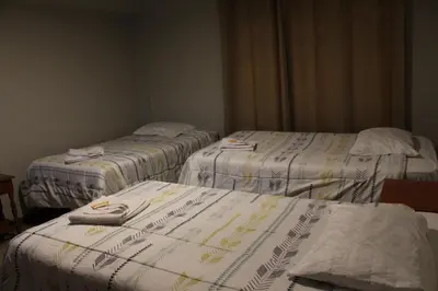three beds in a room with white blankets at LA CASA DEL VISITANTE in Cusco