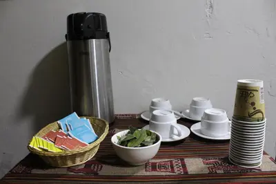 a table with a coffee pot and a bowl of greens at LA CASA DEL VISITANTE in Cusco