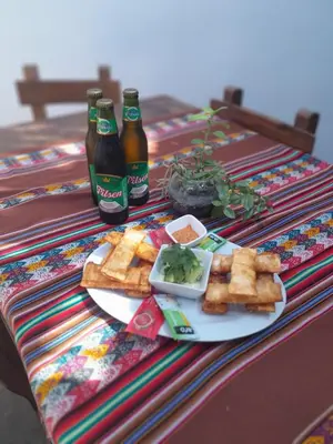 a table with a plate of food and two bottles of beer at Samay77 Ica in Ica