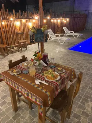 a table with plates of food on it next to a pool at Samay77 Ica in Ica