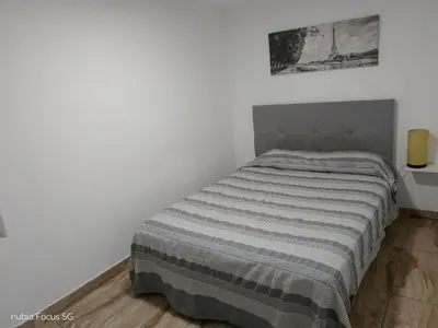 a bed in a white room with a striped blanket at Acogedor departamento en el centro de Barranco in Lima