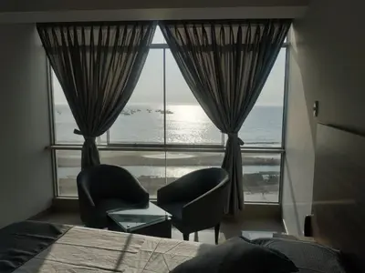 a bedroom with a large window with a view of the ocean at Hotel Terrazas Del Mar in Huacho