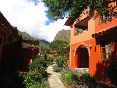 an orange building with flowers in front of a mountain at Tierra Viva Ollantaytambo in Ollantaytambo